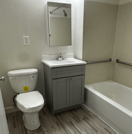 A white toilet with a yellow sticker on it is in a bathroom with a sink and a mirror.