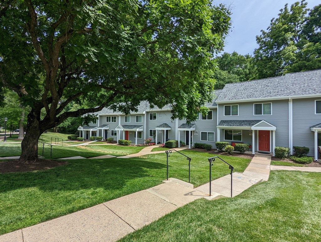 A tree in front of a white house.