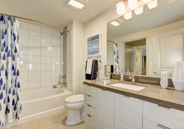 A white toilet sits in a bathroom with a white tub and a sink.