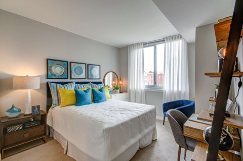 A bedroom with a large bed and a blue chair.