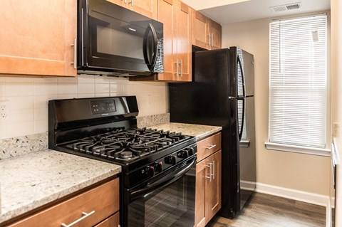 A black stove and refrigerator in a kitchen with wooden cabinets.