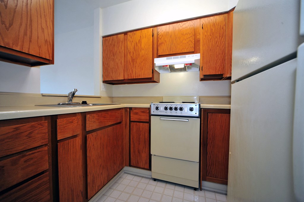 A kitchen with a white stove and wooden cabinets.