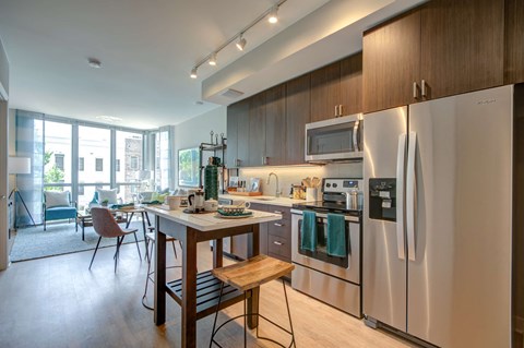 A modern kitchen with stainless steel appliances and wooden furniture.