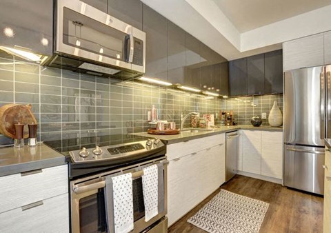 A modern kitchen with a stainless steel refrigerator and a microwave above the stove.
