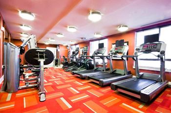 A gym with treadmills, elliptical machines, and a weight bench.