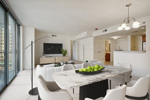 A modern dining room with a marble table and white chairs.