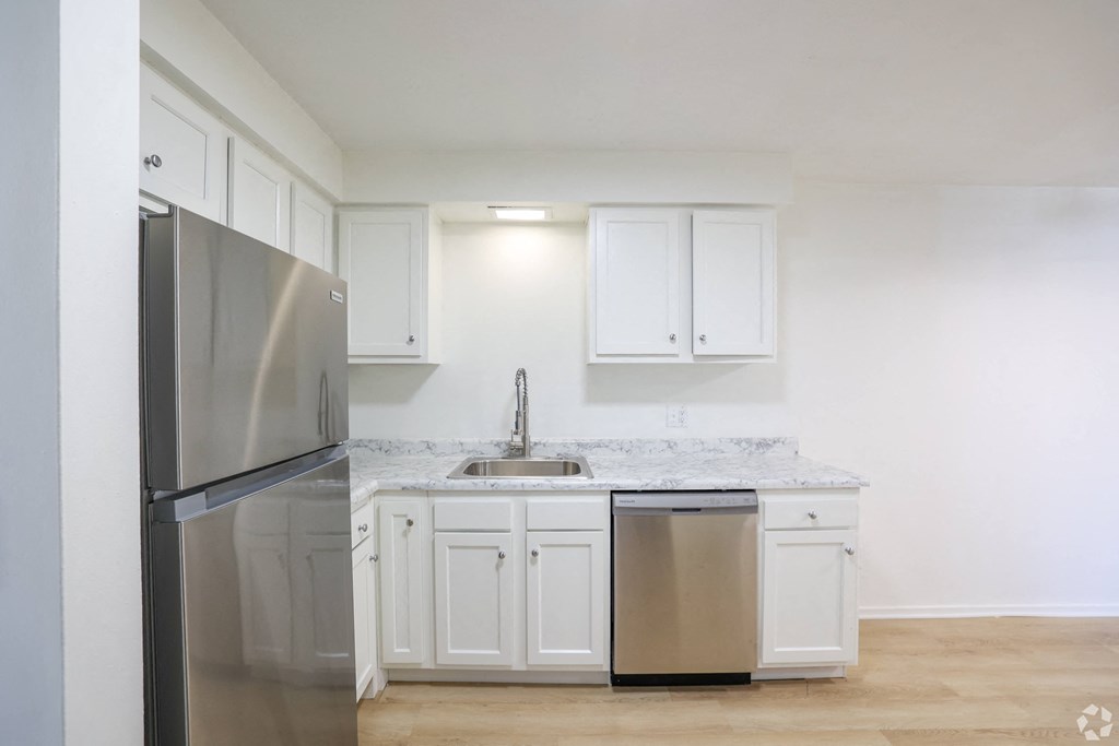 A kitchen with white cabinets and a stainless steel refrigerator.