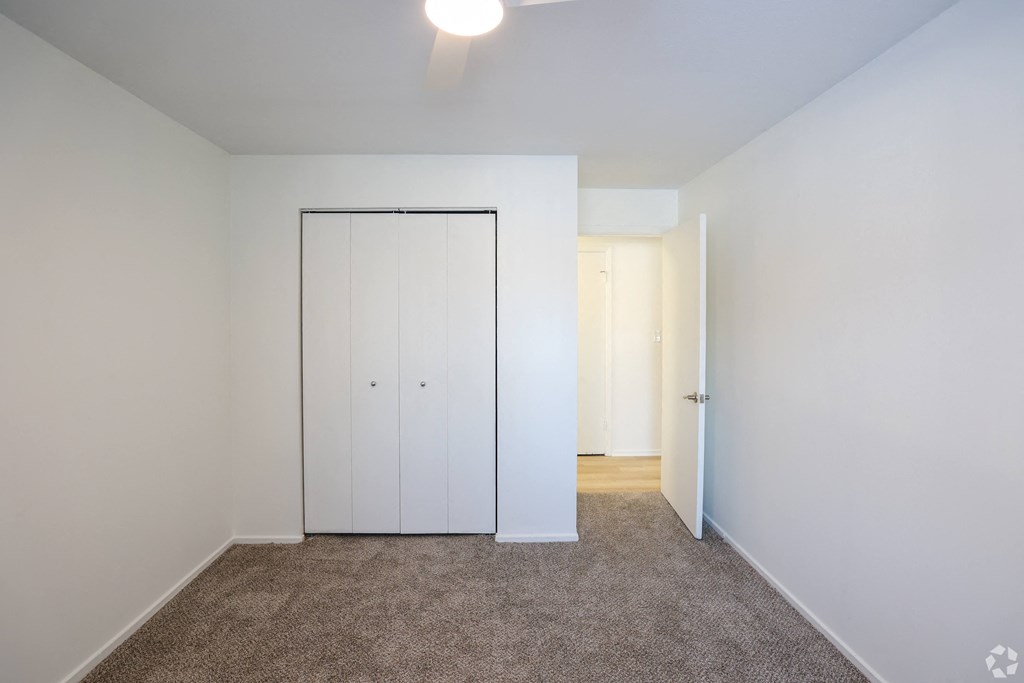 A bedroom with a white wardrobe and carpeted floor.