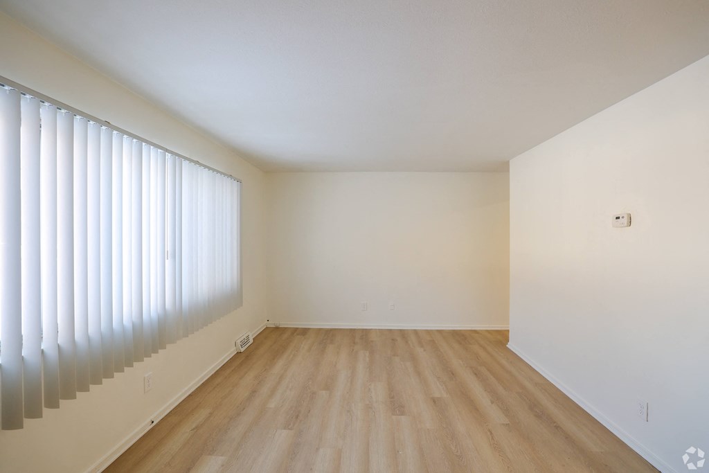 A room with wooden flooring and a window with blinds.