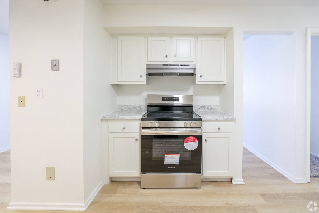 A kitchen with a stainless steel oven and white cabinets.