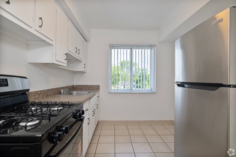 A kitchen with a black stove top and a stainless steel refrigerator.
