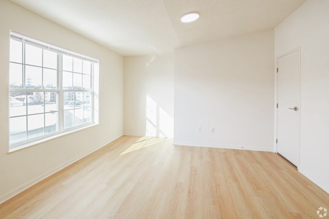 Empty room with wooden floor and large windows.
