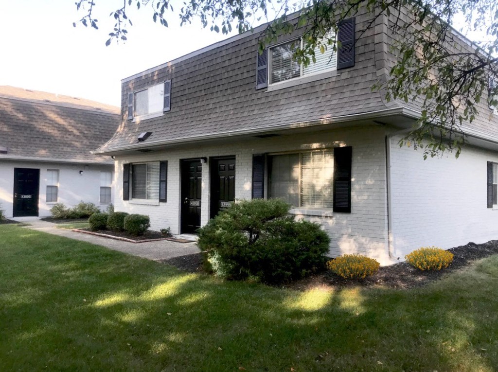 a white house with black shutters and a lawn