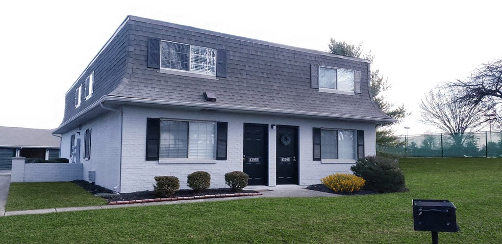 a white house with black shutters and a lawn