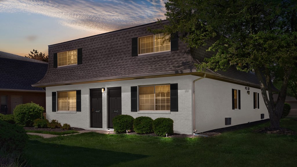 a white house with black shuttered windows and a lawn