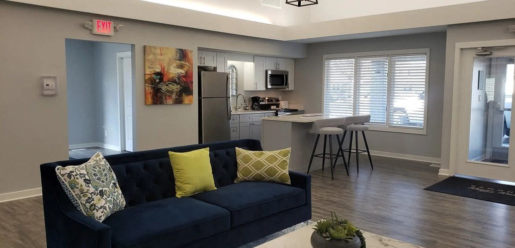 a living room and kitchen with a blue couch and yellow pillows
