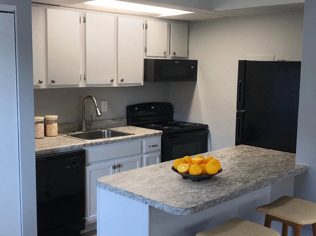 a kitchen with black appliances and a counter with a bowl of fruit