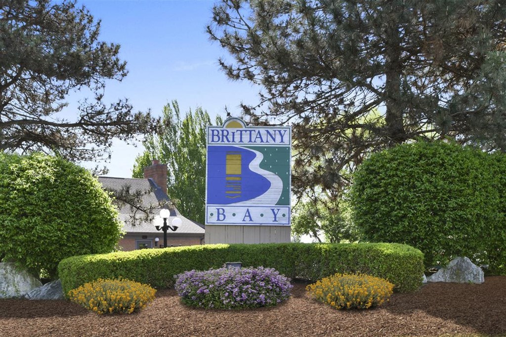 a sign for brittany bay at the front of a garden