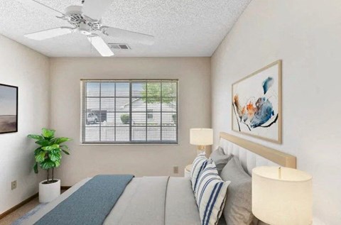A bedroom with a bed, a ceiling fan, and a window with blinds.