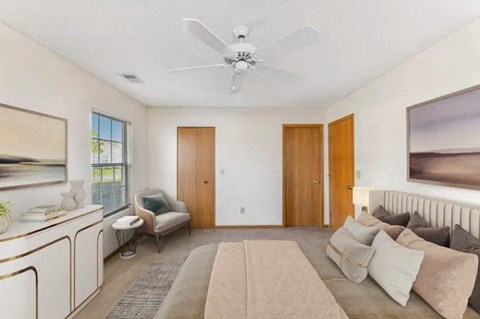 A living room with a beige couch and a white ceiling fan.