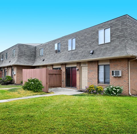 the front of a brick house with a yard and grass