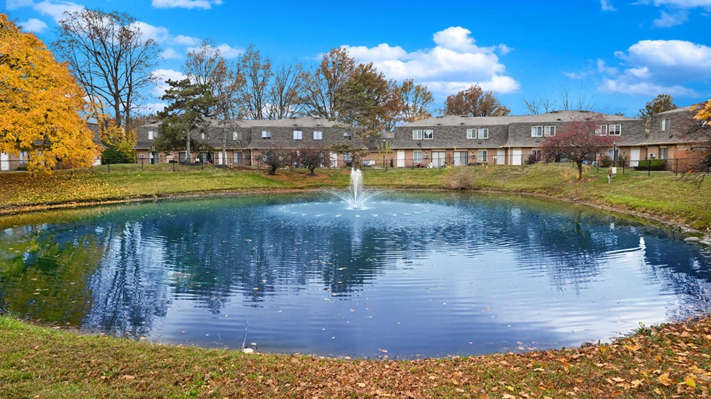 a pond with a fountain in front of a building