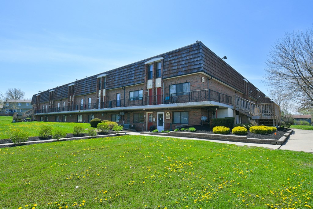 a large brick building with a green lawn in front of it