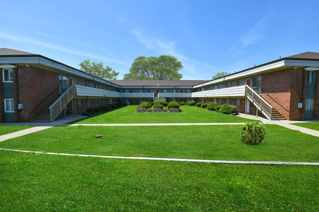 a courtyard in front of a building with green grass