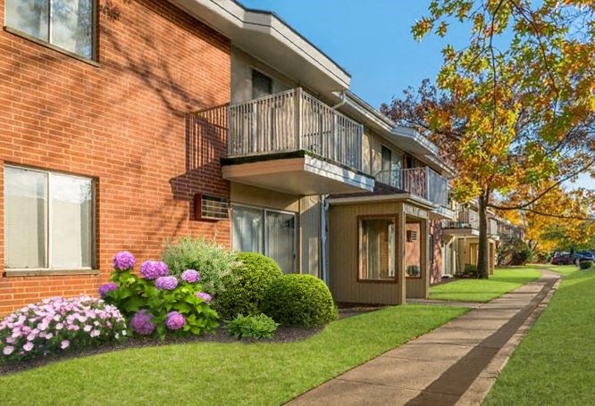 a brick apartment building with a balcony and a sidewalk