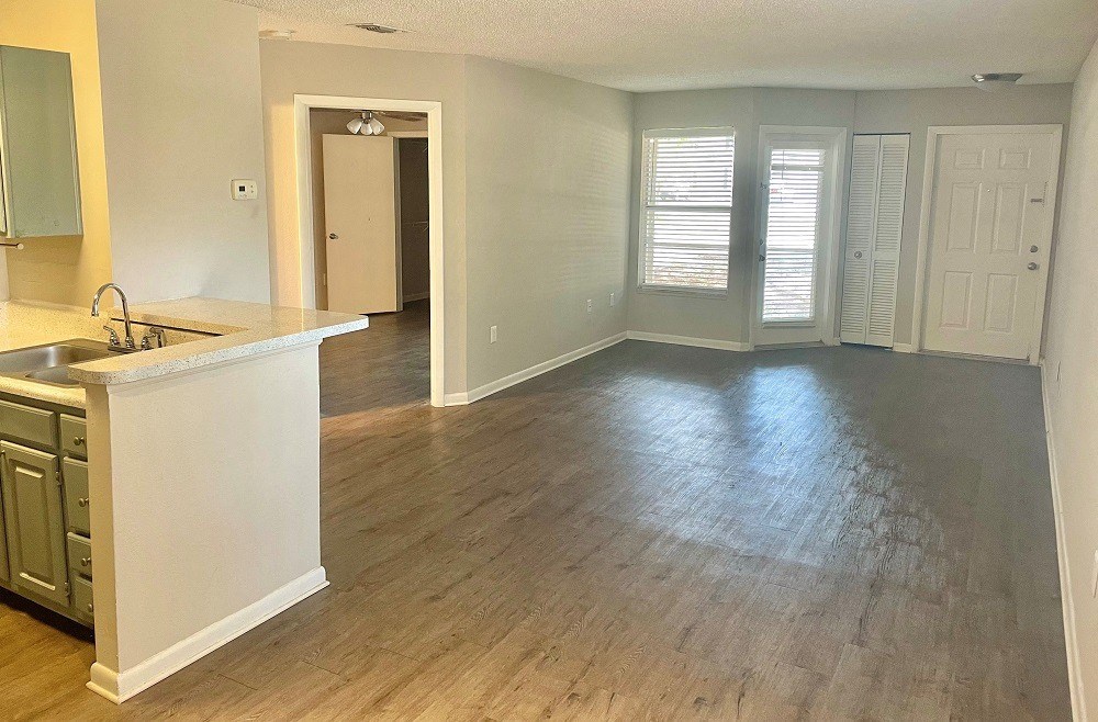 an empty kitchen and living room with a hard wood floor