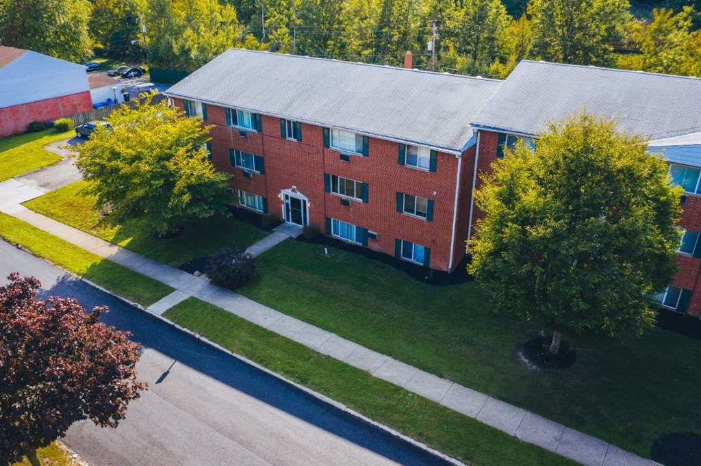 an aerial view of a brick building with green grass and trees