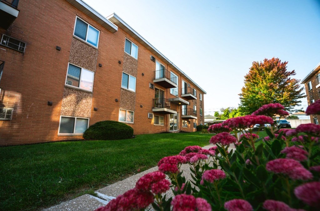 a brick building with grass and flowers in front of it