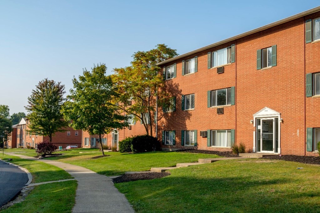 a brick building with green grass and trees