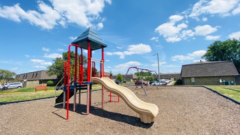 A playground with a red and blue structure and a yellow slide.