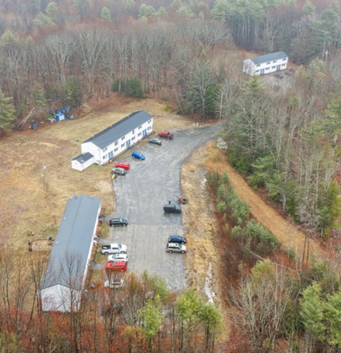 Aerial view of Clark's Mills apartment buildings and parking along a wooded driveway in Hollis, Maine