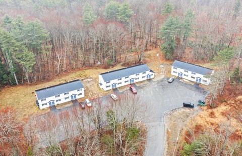 Fall aerial view of Countryside's three two-story apartment buildings around a cul-de-sac parking lot, surrounded by woods