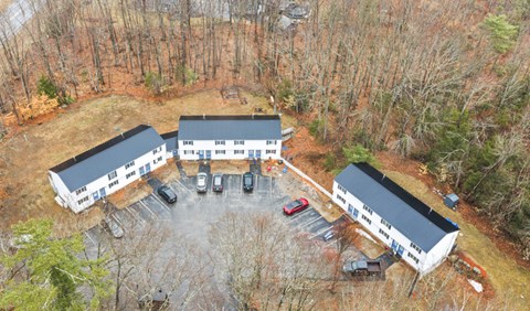 Fall aerial view of Hilltop's two-story apartment buildings around a parking lot, backed by woods