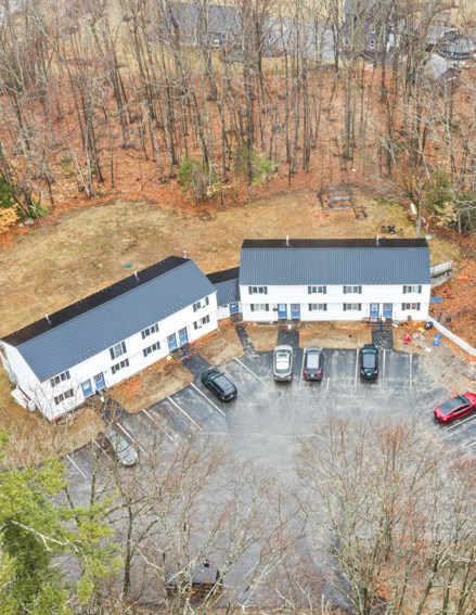 Aerial view of Hilltop apartment buildings with parking at the door and wooded surroundings
