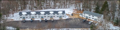 Winter aerial view of Saco River apartments at 270 Bar Mills Road, a long two-story building and a second building beside a paved lot