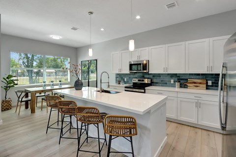 an open kitchen with white cabinets and a large island with stools