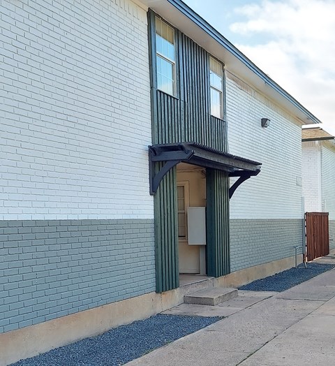 A white and blue building with a black awning.