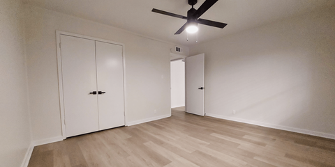 an empty living room with white walls and a ceiling fan
