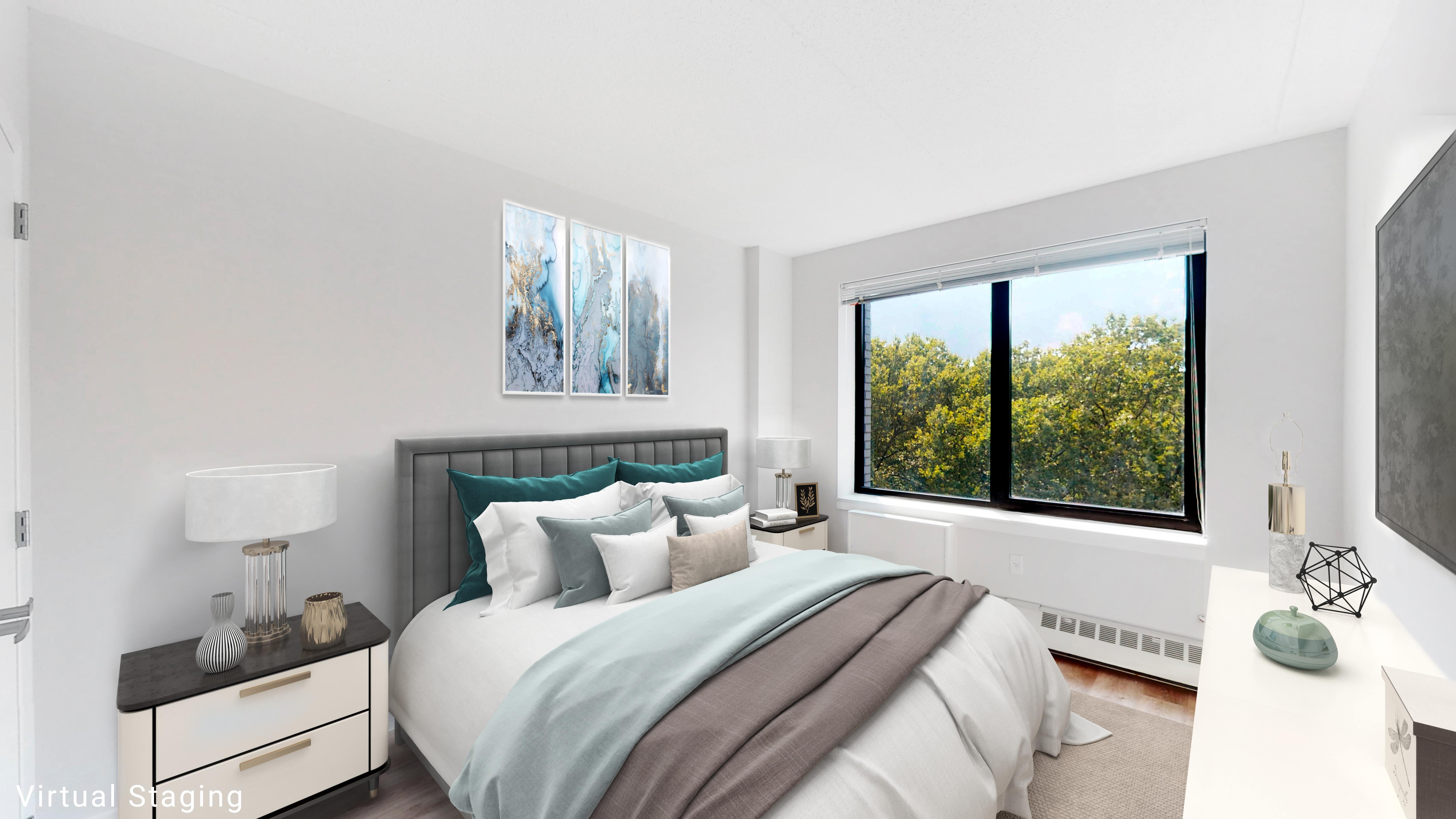 A bedroom with a large bed and a window overlooking trees.