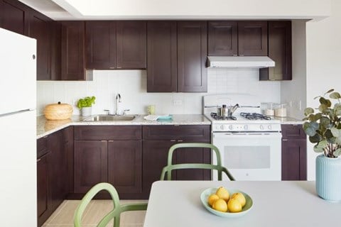 A kitchen with a white fridge, white stove, and brown cabinets.