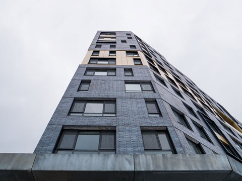A tall building with a grey facade and windows of varying sizes.