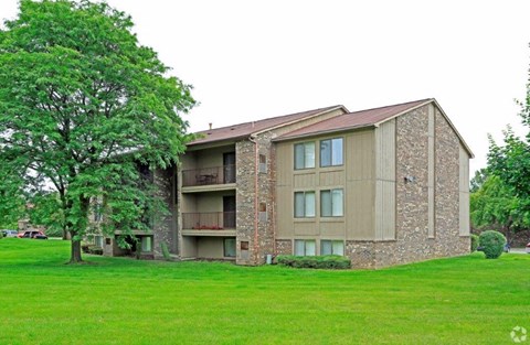 a building with a green lawn and a tree