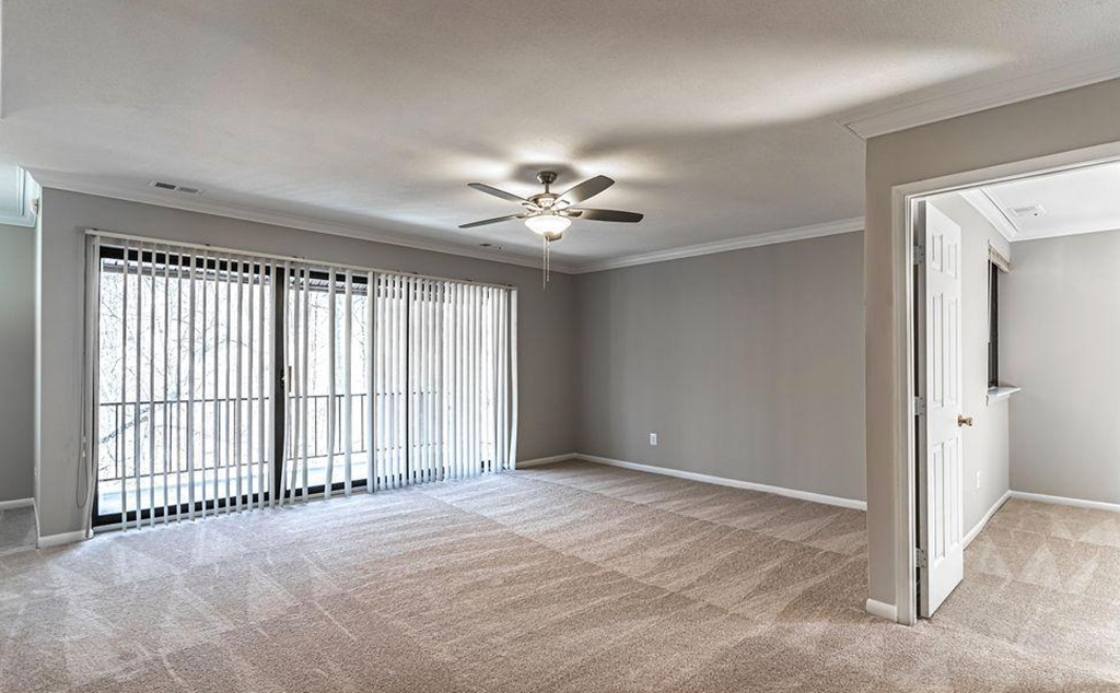 an empty living room with a ceiling fan