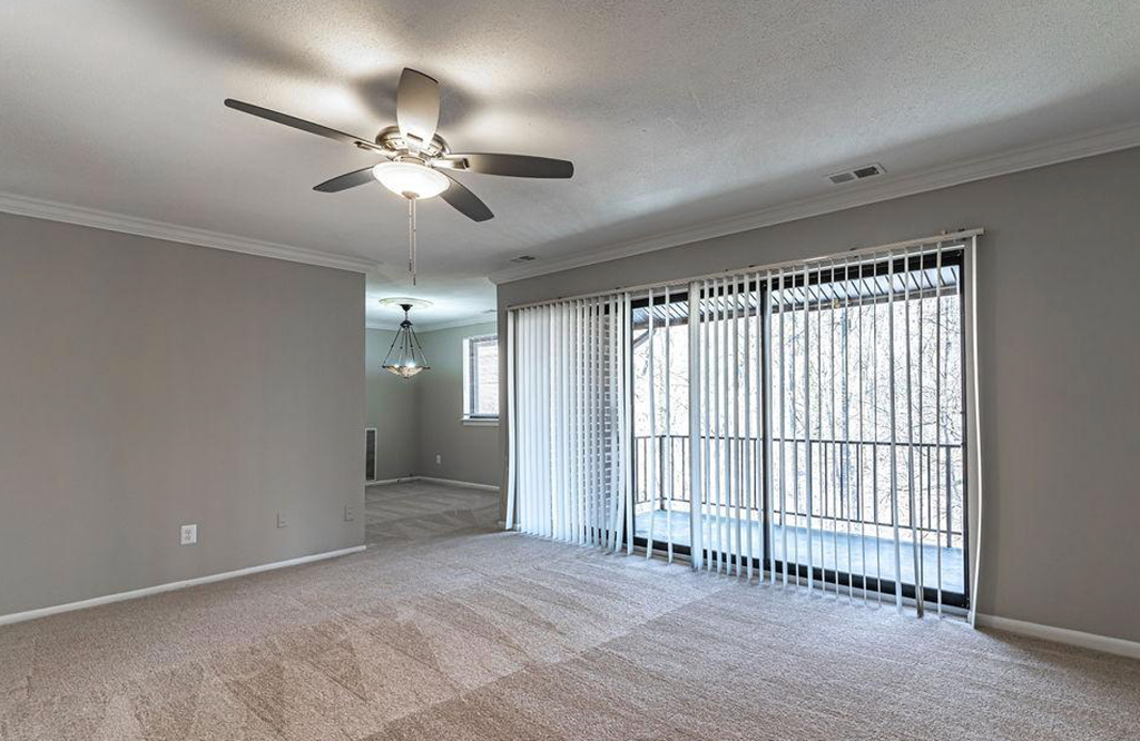an empty living room with a ceiling fan and a large window