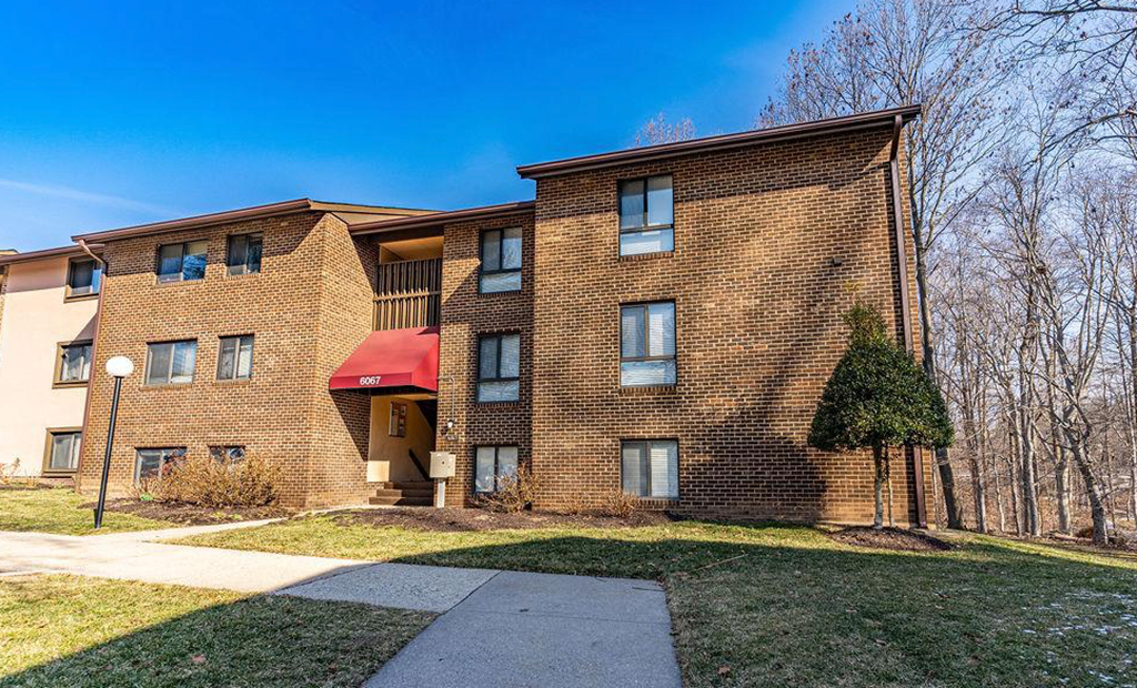 a brick apartment building with a sidewalk and grass
