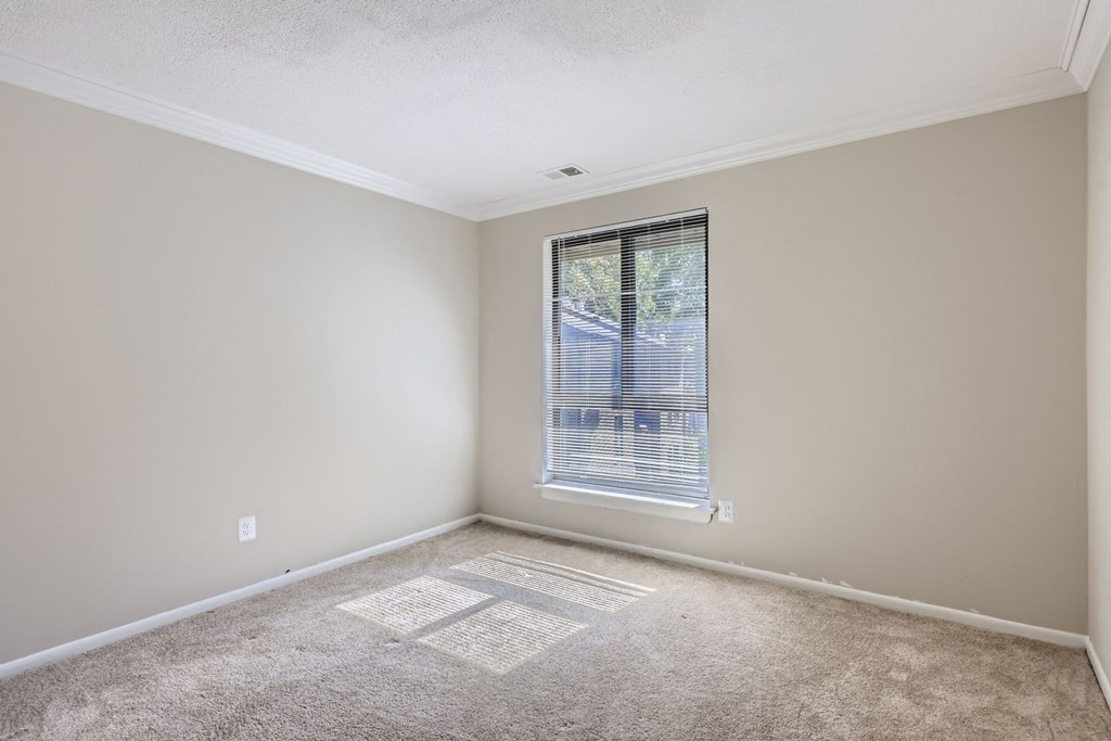 an empty room with a window and carpet